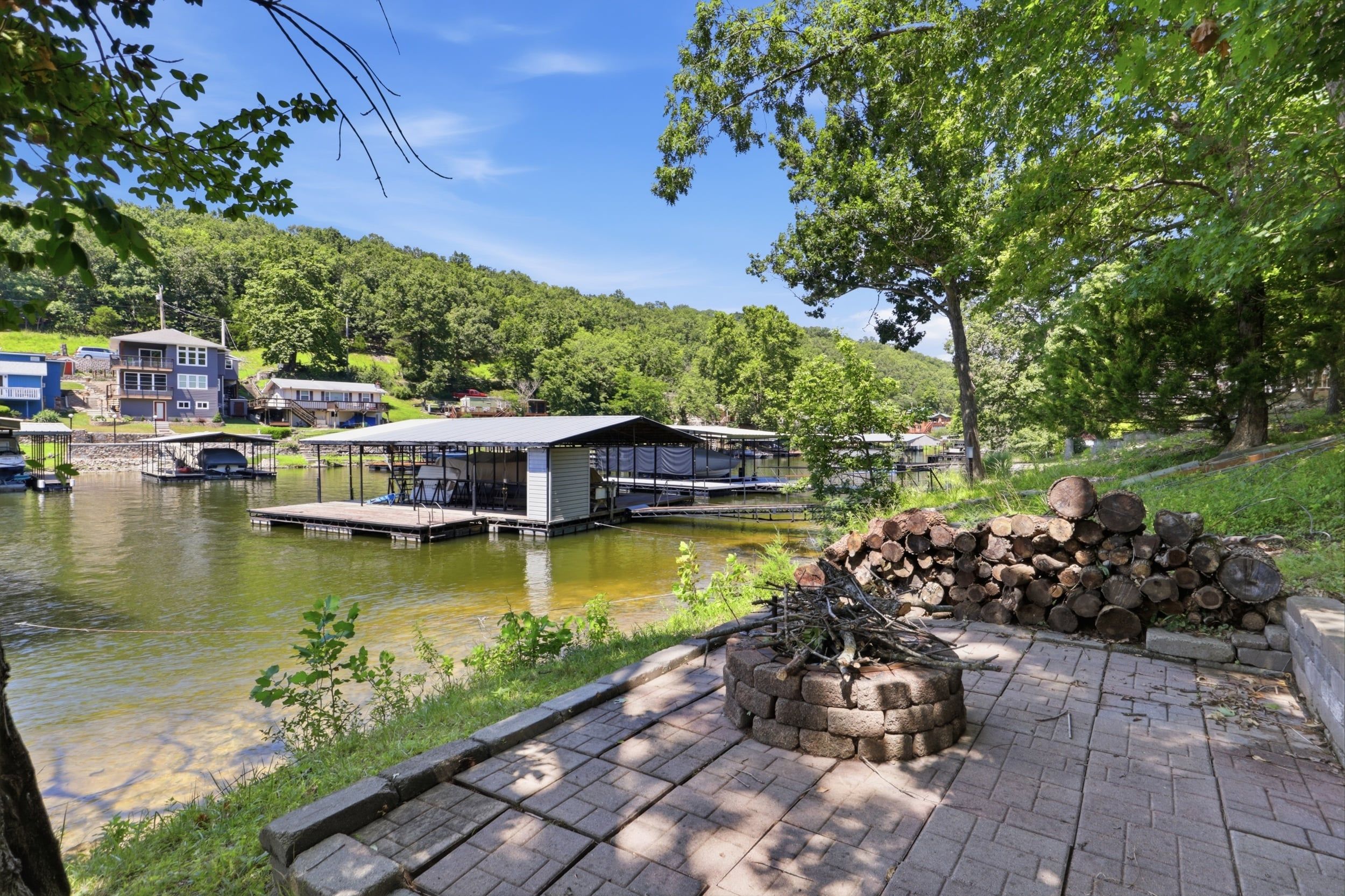 A lakeside property with a dock, a fire pit, and a building with a covered patio area.