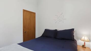 Une chambre à coucher avec un lit, une table de chevet avec une lampe, une porte en bois et un élément décoratif mural.