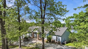 A two-story house with a gravel driveway and a lawn. - Big Lakefront Lodge With Private Dock, 2 Slips, Game Room, Firepit & More at 11mm (Sunrise Beach)