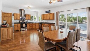 A spacious kitchen with wooden cabinets, a central island, and a dining area with a large table and chairs. - Big Lakefront Lodge With Private Dock, 2 Slips, Game Room, Firepit & More at 11mm (Sunrise Beach)