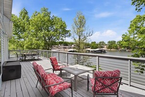 Eine Terrasse mit Sitzgelegenheiten im Freien, Blick auf einen Fluss und ein Gebäude im Hintergrund.
