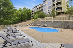 A pool area with lounge chairs, a wooden deck, and a building with multiple balconies. - Blissful Lake Life at the 24mm Playground, 2 Pools & Trailer Parking (Osage Beach)