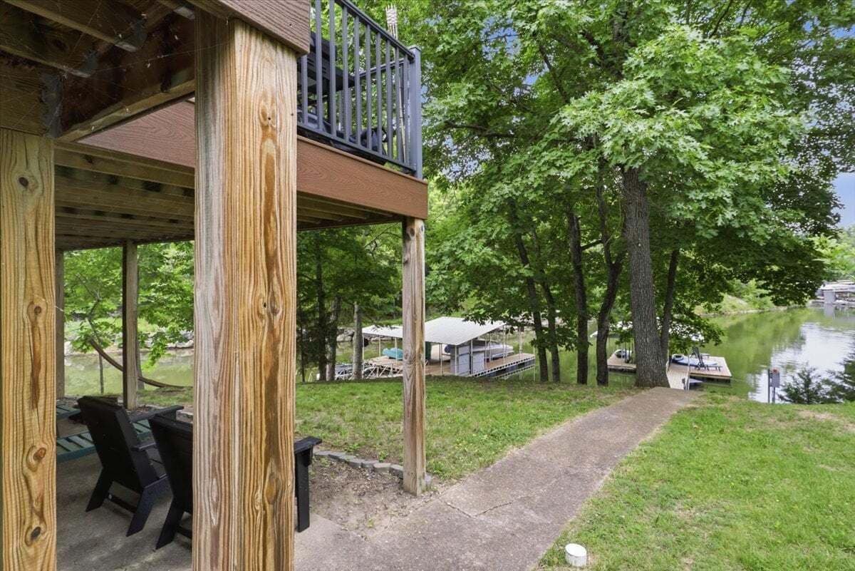 Eine Holzterrasse mit Geländer, die auf eine Rasenfläche und ein Gewässer blickt.