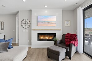 A living room with a fireplace, a clock, and a painting of a beach scene. - Main Channel Views, Resort Pools & Boat Slip at Topsider's 19mm (Osage Beach)
