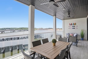 A spacious balcony with a view of a bridge and water, furnished with a table and chairs, and a small potted plant. - Main Channel Views, Resort Pools & Boat Slip at Topsider's 19mm (Osage Beach)