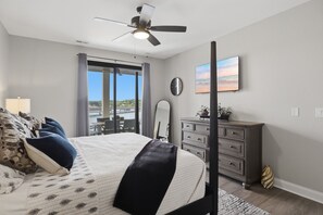 A bedroom with a bed, a dresser, a clock, a painting, and a view through a sliding door. - Main Channel Views, Resort Pools & Boat Slip at Topsider's 19mm (Osage Beach)