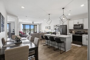 A modern kitchen with a central island, black bar stools, and a dining area with a large table and chairs. - Main Channel Views, Resort Pools & Boat Slip at Topsider's 19mm (Osage Beach)