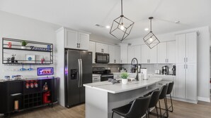 A modern kitchen with white cabinets, a central island with bar stools, a built-in microwave, and a stainless steel refrigerator. - Main Channel Views, Resort Pools & Boat Slip at Topsider's 19mm (Osage Beach)