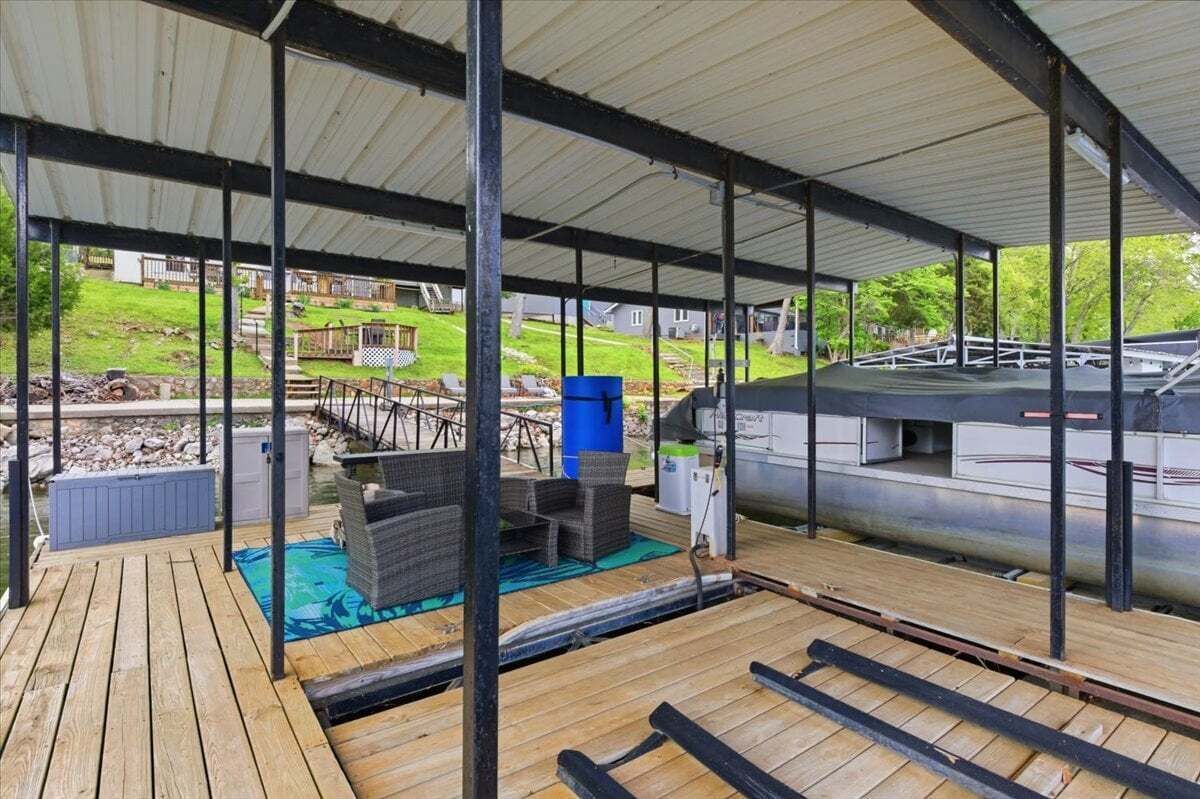 A covered outdoor deck with a pool, lounge chairs, and a grill area.