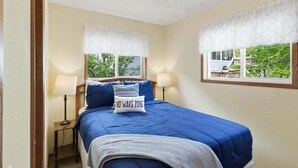 A bedroom with a bed, two bedside lamps, a ceiling fan, and a window with a view of greenery. - Lakefront Fun With Private Dock, Firepit, Swim Mat, Kayaks & Screened Lake Room (Gravois Mills)