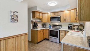 A compact kitchen with wooden cabinets, a microwave, an oven, and a sink. - Lakefront Fun With Private Dock, Firepit, Swim Mat, Kayaks & Screened Lake Room (Gravois Mills)