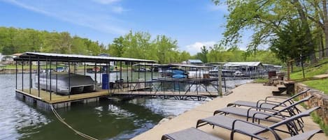 A dock with covered structures, a waterway, and a row of benches.