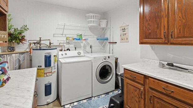 A laundry area with a washing machine, dryer, and stacked laundry baskets. - Lakefront Fun With Private Dock, Firepit, Swim Mat, Kayaks & Screened Lake Room (Gravois Mills)