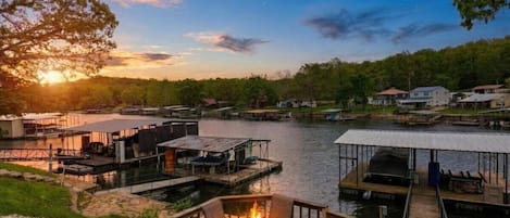 A lakeside property with a dock, outdoor seating, and a fire pit.