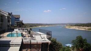 Zona de piscina con vista a un río y colinas lejanas.