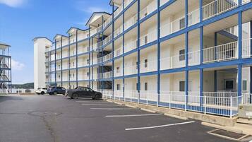 Un motel à plusieurs étages, doté de balcons, d’un parking et offrant une vue sur un ciel dégagé.