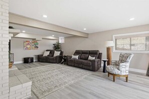 Ein Wohnzimmer mit zwei Sofas, einem gemusterten Teppich, einem Beistelltisch und einem Sessel.