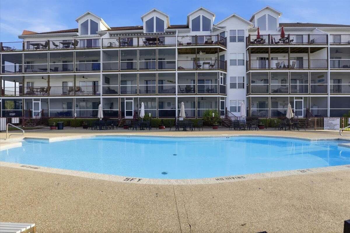 A multi-story hotel with a swimming pool, balconies, and outdoor seating.