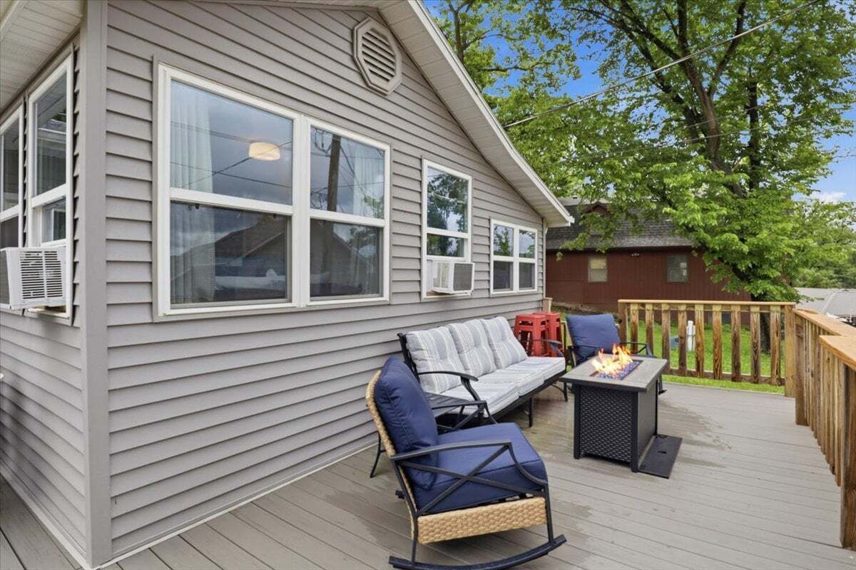 Ein Haus mit Terrasse, Feuerstelle und Gartenmöbeln.