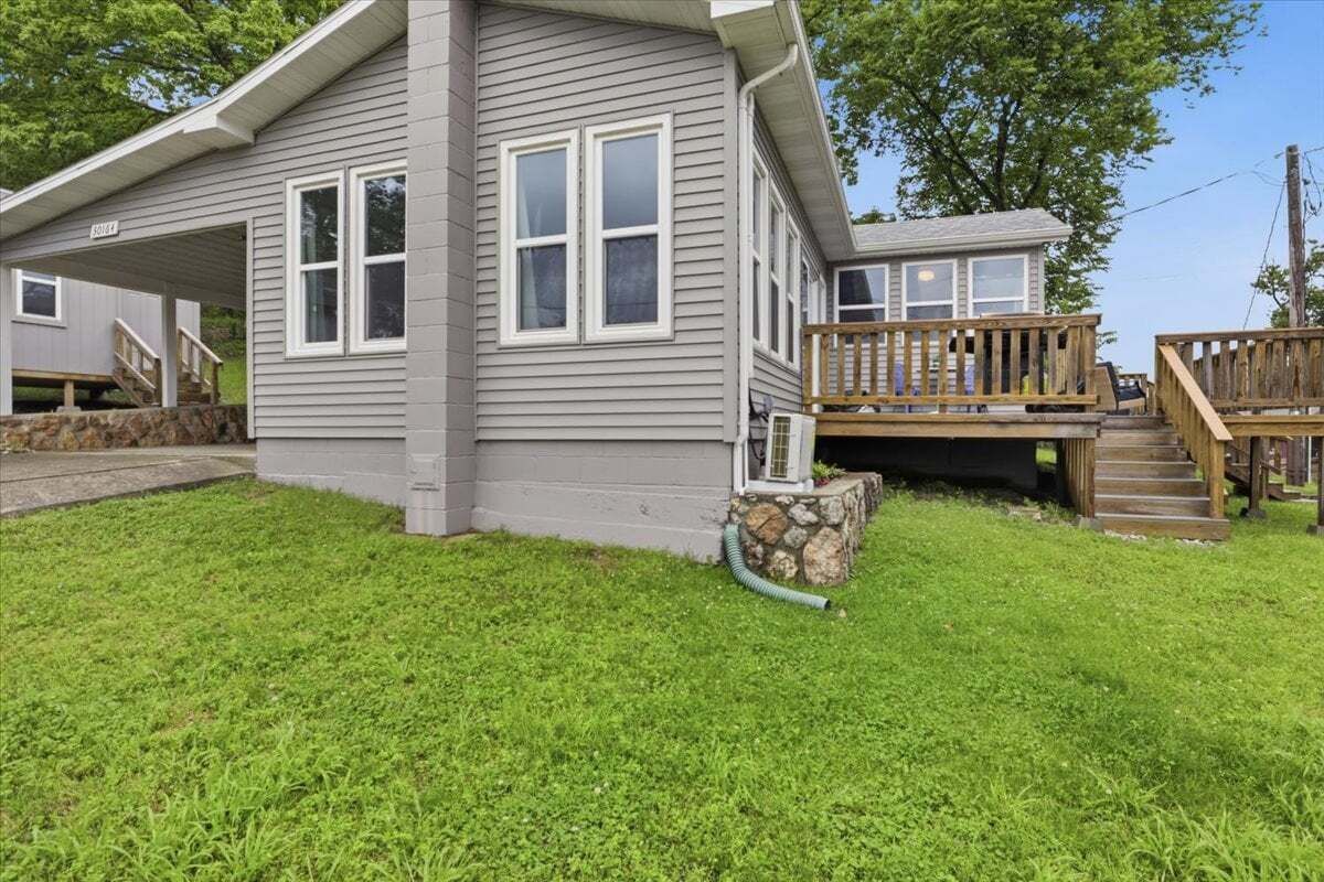 A two-story house with a covered porch and a stone foundation.