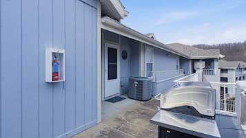 A building with a blue exterior, a fire extinguisher mounted on the wall, and a covered outdoor grill area.