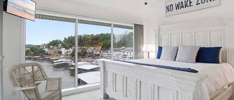 Un dormitorio con cama, una silla, un televisor y vistas al frente marítimo.