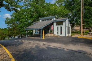A building with a covered entrance, a flag, and a number '1442' on the side. - Cozy Lakefront Condo w/ Dock Slip, Fishing & Hot Tub (Osage Beach)