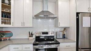 A kitchen with white cabinets, a stainless steel stove, and a refrigerator. - Lakefront Main Channel Home With Private Dock, 2 Slips, Big Views & Garage Parking (Lake Ozark)