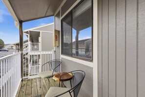 A balcony with two chairs and a small table, a railing, and a view of a parking lot. - Lakefront Condo With Boat Slip, Heated Pool & Boat Launch (Osage Beach)