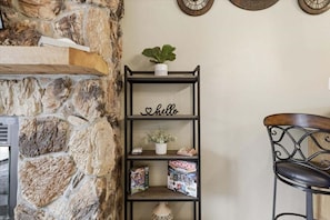 A stone wall, a shelf with a 'hello' sign, a plant, and a Monopoly board game. - Lakefront Condo With Boat Slip, Heated Pool & Boat Launch (Osage Beach)