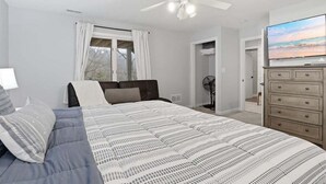 A bedroom with a bed, a ceiling fan, a dresser, and a television. - Lakefront Near Party Cove w/ Dock, Kayaks, Bunk Room & Multi-level Decks (Osage Beach)