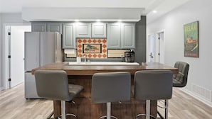 A modern kitchen with a central island, bar stools, and a coffee machine. - Lakefront Near Party Cove w/ Dock, Kayaks, Bunk Room & Multi-level Decks (Osage Beach)