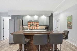 A modern kitchen with a central island, bar stools, and a coffee machine. - Lakefront Near Party Cove w/ Dock, Kayaks, Bunk Room & Multi-level Decks (Osage Beach)