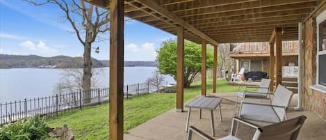 A covered outdoor seating area with a view of a lake and hills.