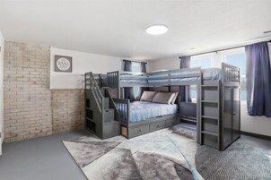 A bunk bed room with a staircase, a 'NO WAKE ZONE' sign, and a window with curtains.