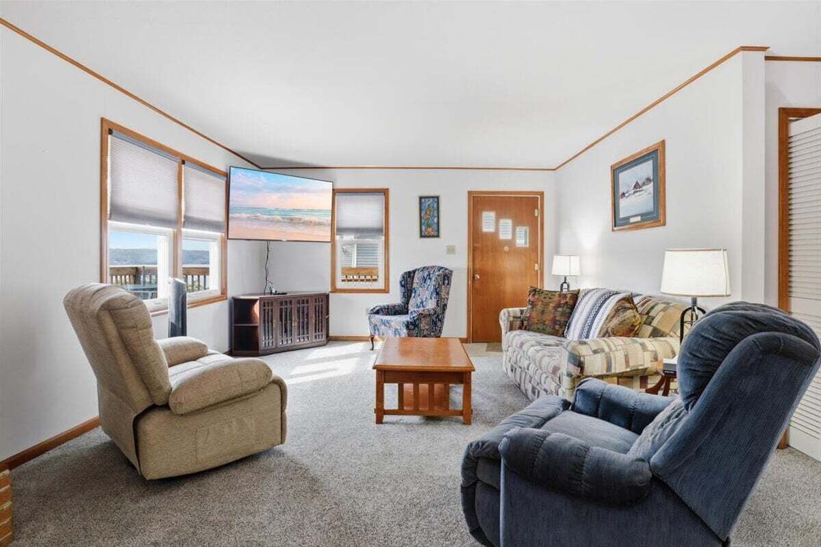 A living room with a sofa, armchairs, a coffee table, a television, and a door with a window.