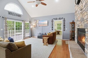 A living room with a fireplace, a sofa, a coffee table, and a TV. - Private Cove Dock, PWC Lifts, Huge Deck & Family Fun (Climax Springs)