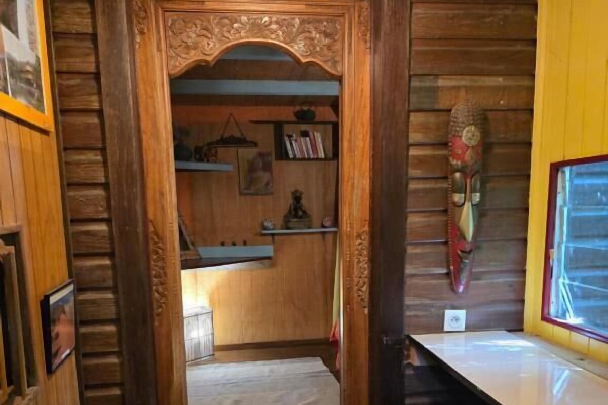A narrow hallway with a wooden door leading to a room with a window.