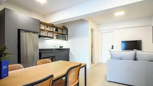 A modern kitchen with a refrigerator, microwave, and dining area with chairs and a table. - Apt. in Condo w/ City View in Downtown Ubs0502 (Florianópolis)