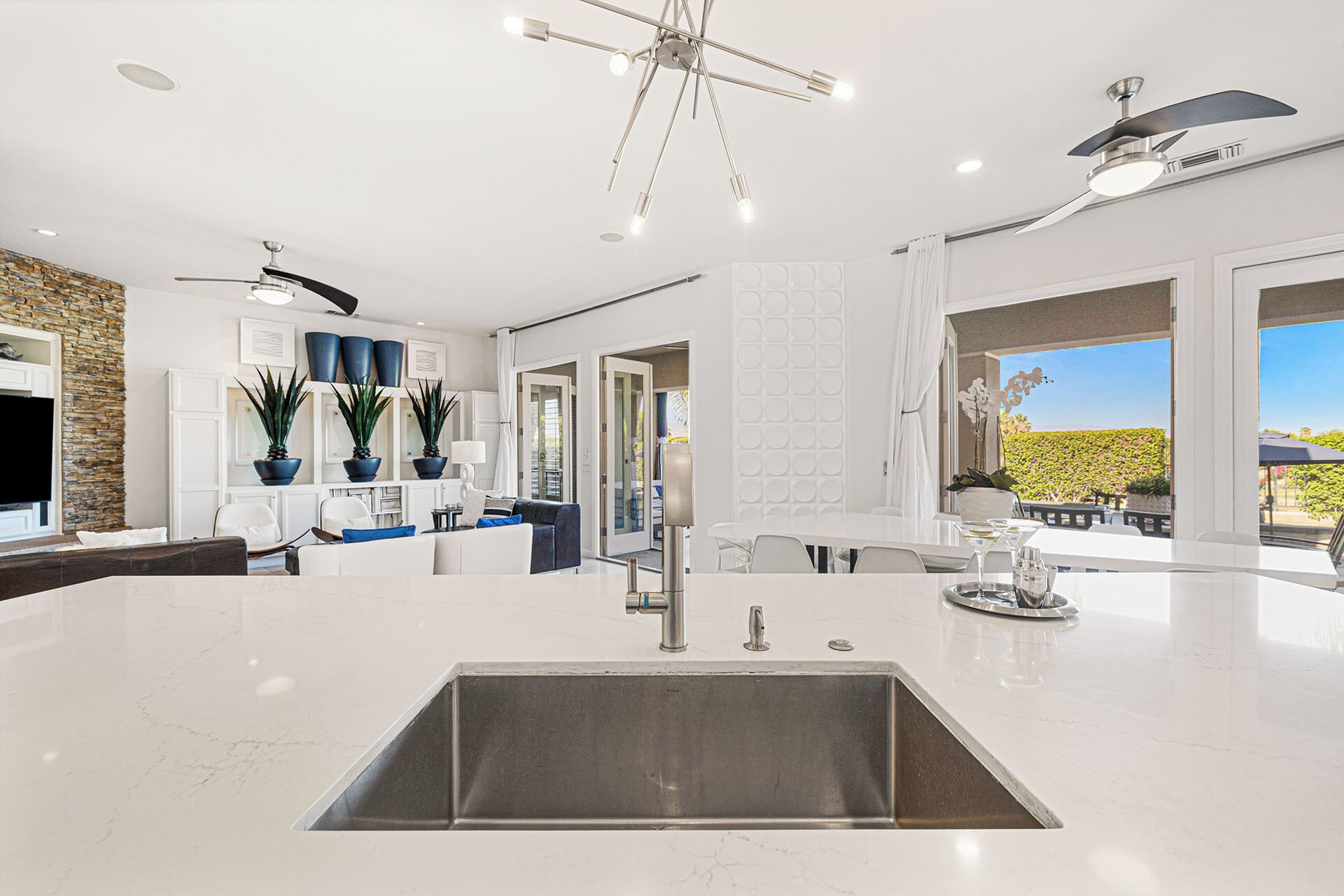A modern kitchen with a central island, a built-in sink, and a ceiling fan.