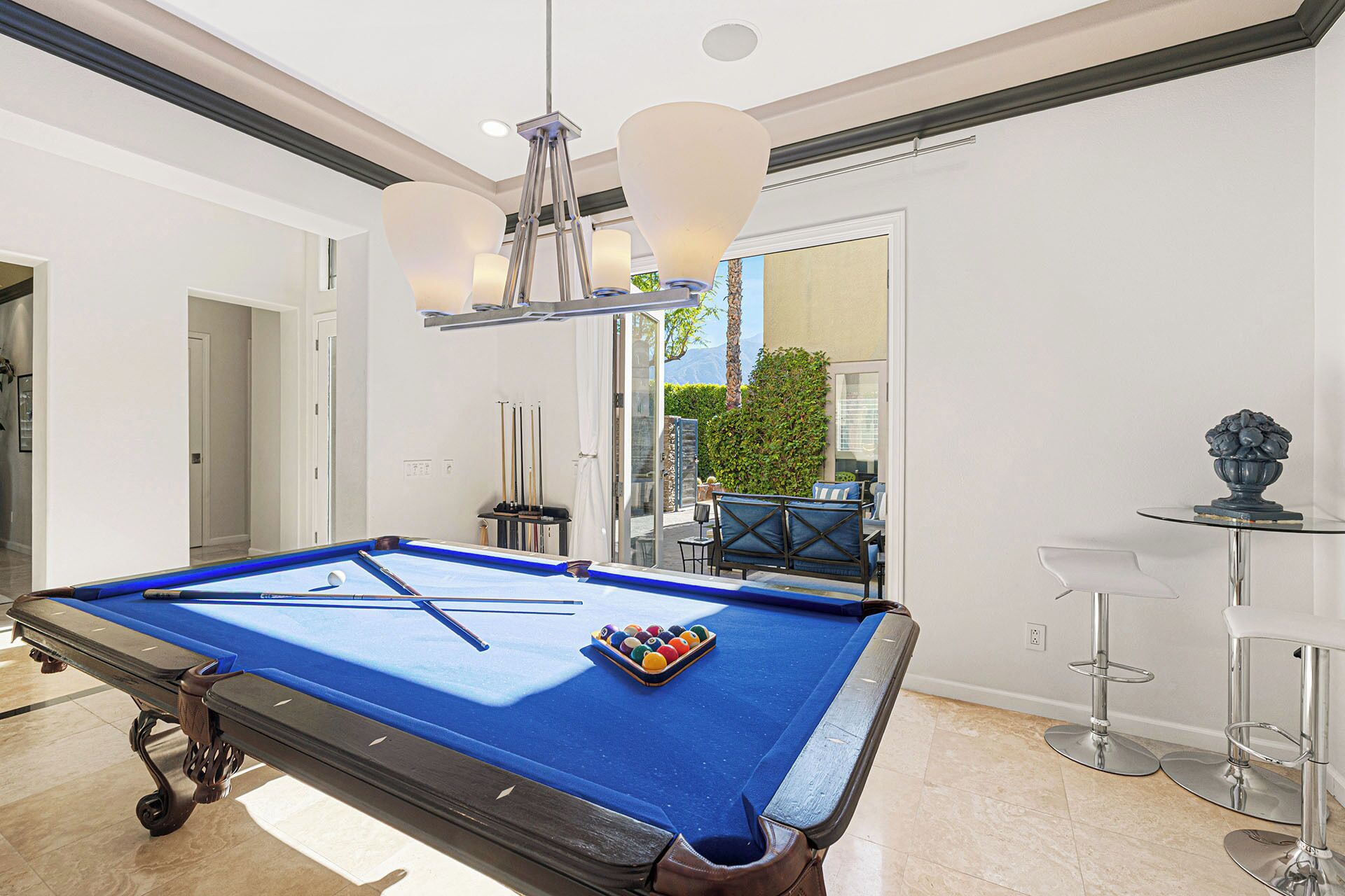 A pool table with a blue felt surface, a set of pool cues, and a rack of billiard balls.