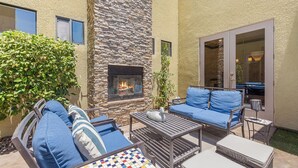 An outdoor patio with a stone fireplace, blue cushioned seating, and a small table. - Casa Sonora Grande - A Palm Springs 6 bedroom gem! (Palm Springs)