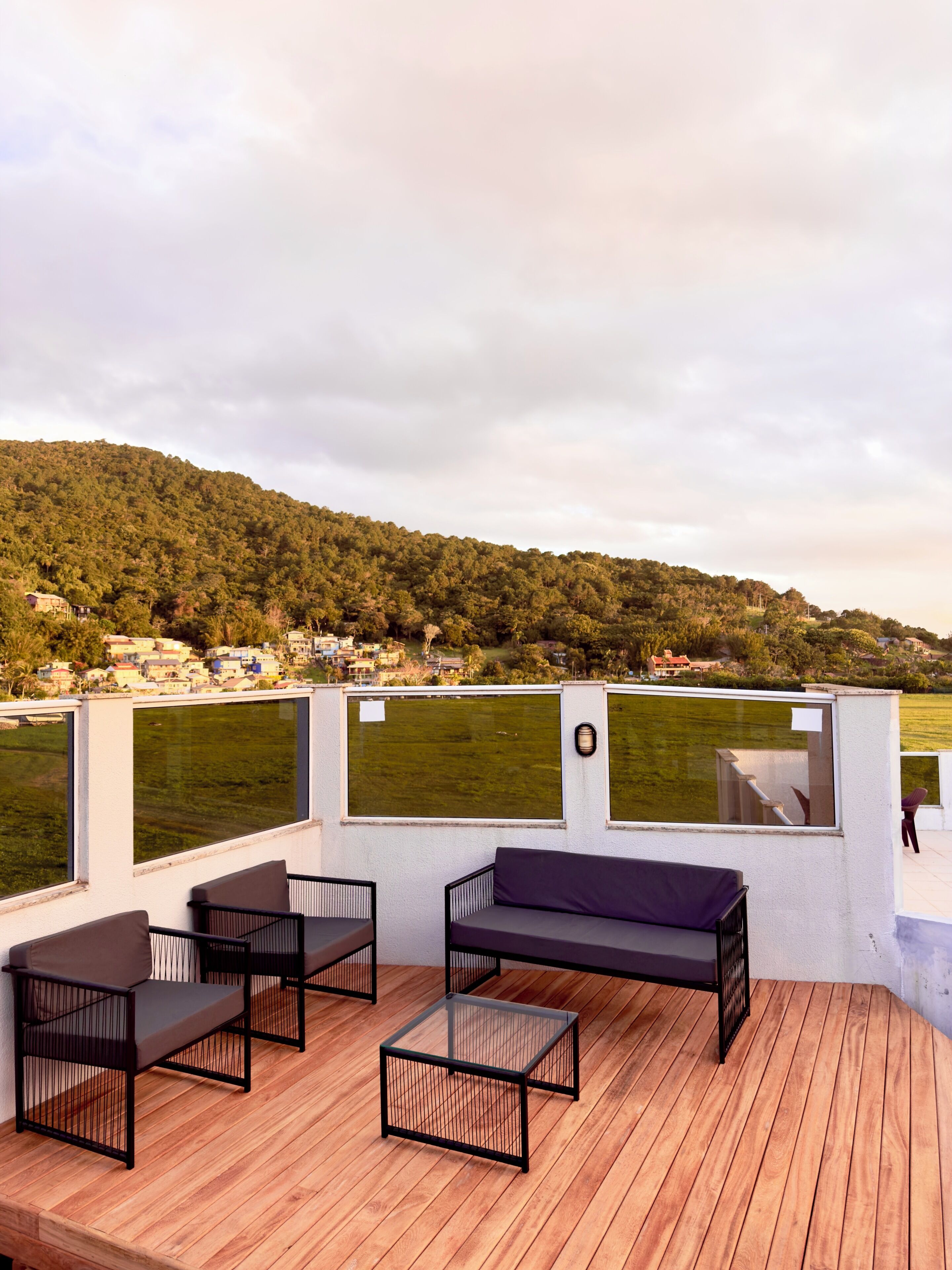 Une terrasse avec des meubles d’extérieur, une vue sur un champ verdoyant et une colline en arrière-plan.