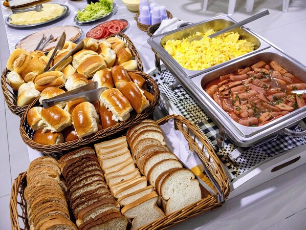 A buffet with various food items including bread, eggs, and sausages.