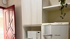 Een keuken met een witte koelkast, een magnetron en een kast.
