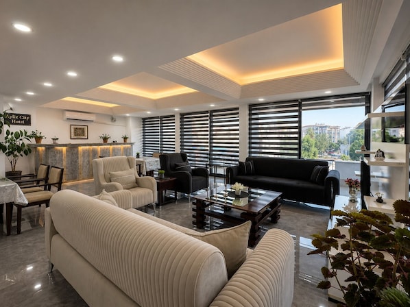 Un moderno vestíbulo de hotel con un sofá, sillones, una mesa de centro y un mostrador de recepción.