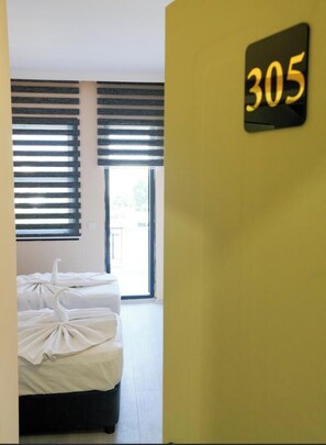 A hotel room with a bed, a window with blinds, and a wall-mounted sign with the number 305. - Ayliz City Otel (Manavgat)