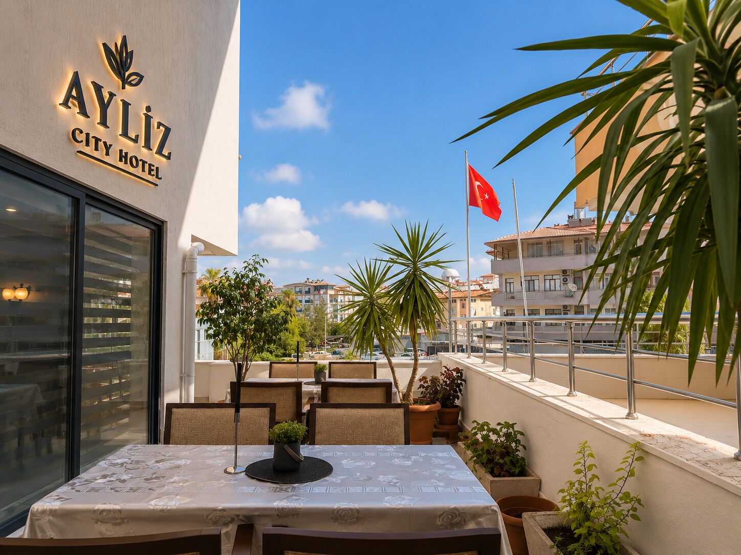 An outdoor seating area of the Ayliz City Hotel with a view of the cityscape and a flag.