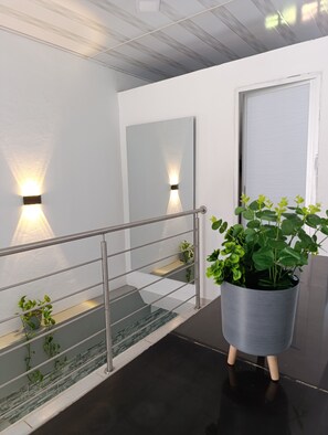 Ein modernes Interieur mit Metallgeländer, einer Topfpflanze und einer Wandleuchte.