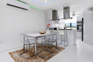 A modern kitchen with a dining area, featuring a white table, clear chairs, and a central decorative bowl. - AQUATIKA!!!5 Pools, Hot Tubs, Lazy River, Beach, Tennis, Mini golf, pickleball (Mediania Alta)
